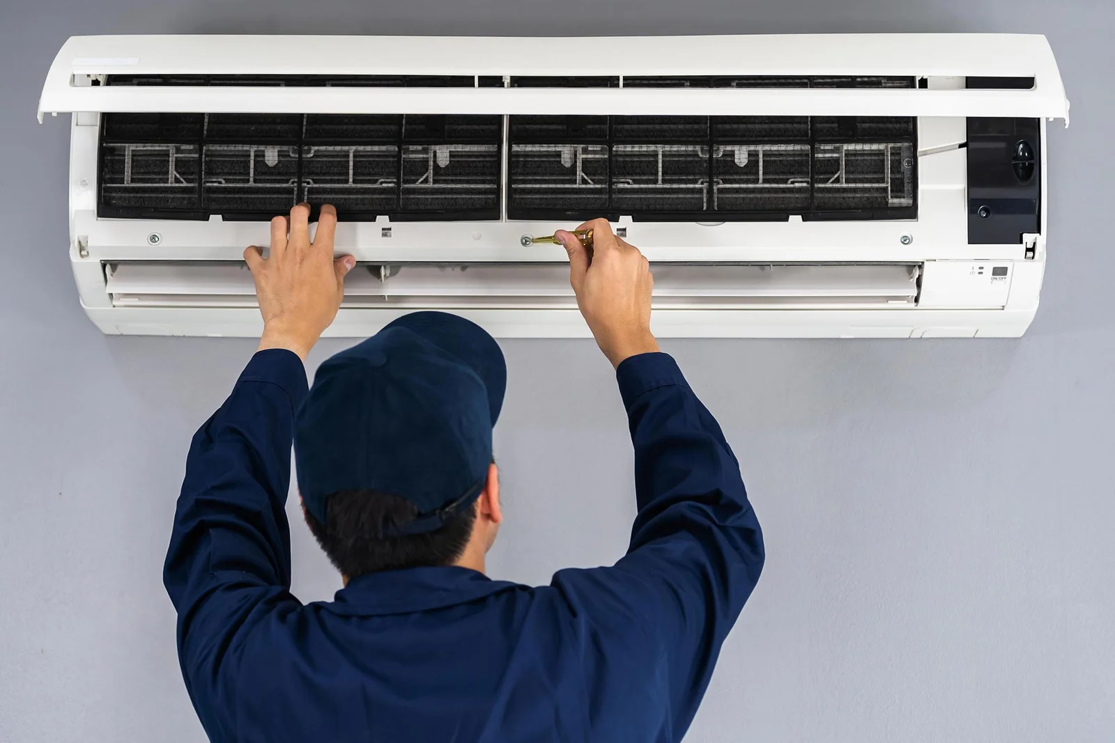 HVAC specialist inspects and cleans the internal components of a wall air conditioning unit in a Peoria home