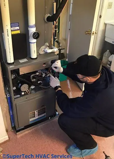 HVAC technician working on an indoor furnace system, the kind of licensed service Peoria Furnace Repair provides