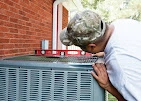 Technician working on an outdoor HVAC condenser unit at a residential property in the Peoria service area